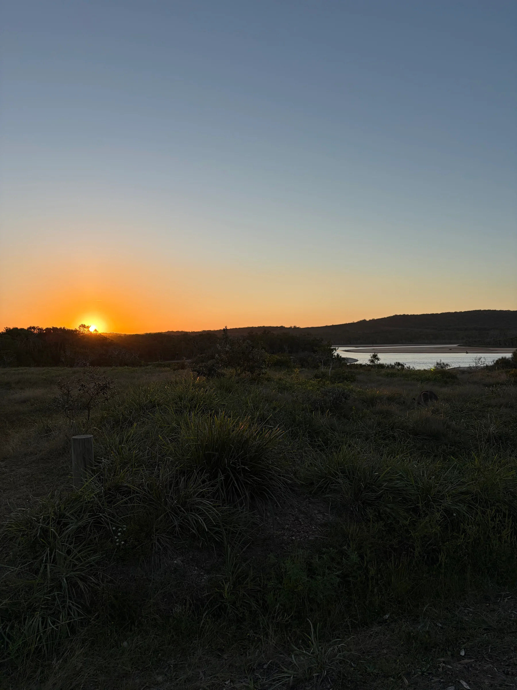 Sun setting over scrub and a lagoon beside the camp