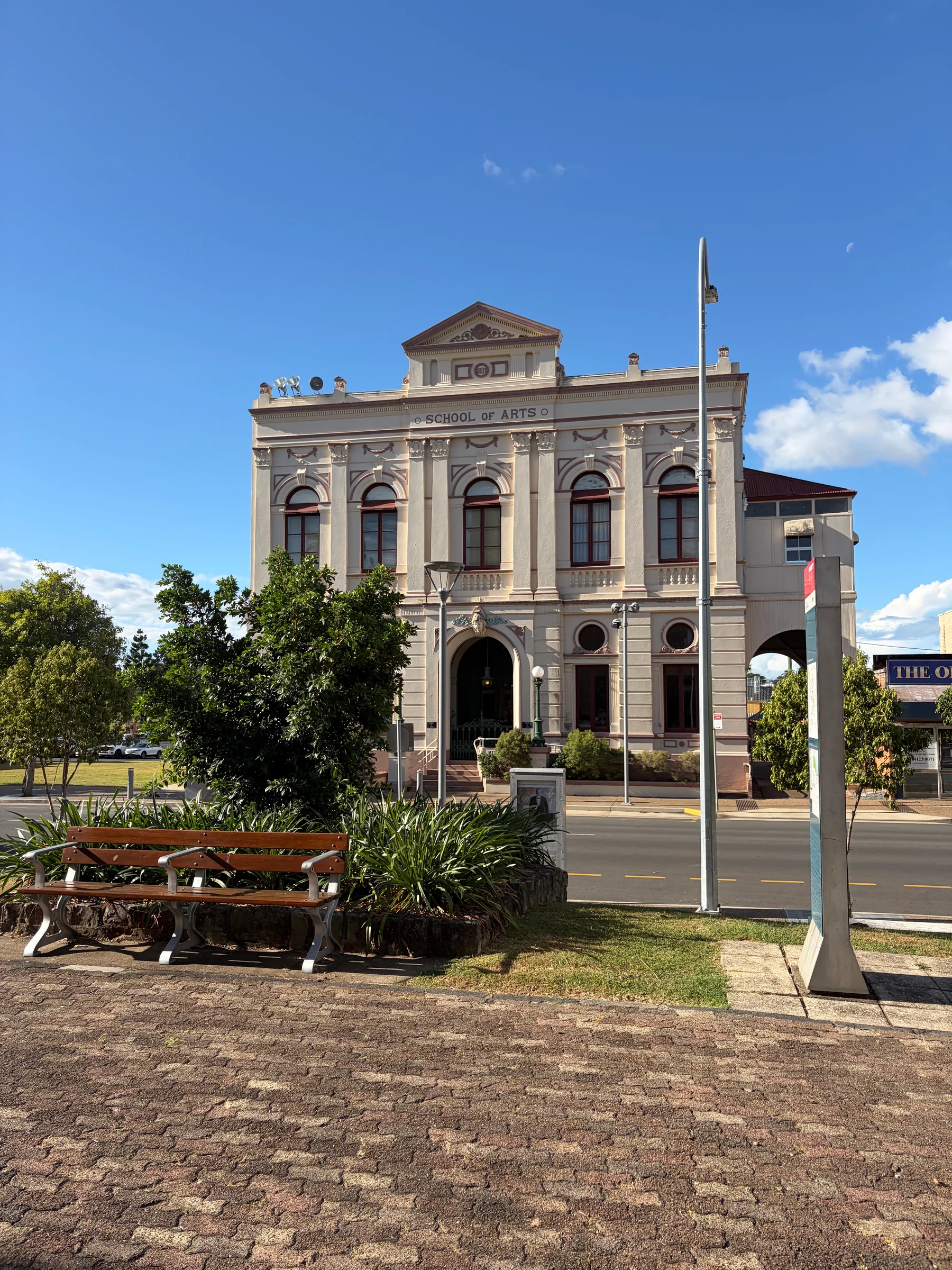 A grand nineteenth-century sandstone building with a colonnaded facade and ornate arched windows, blue sky above.