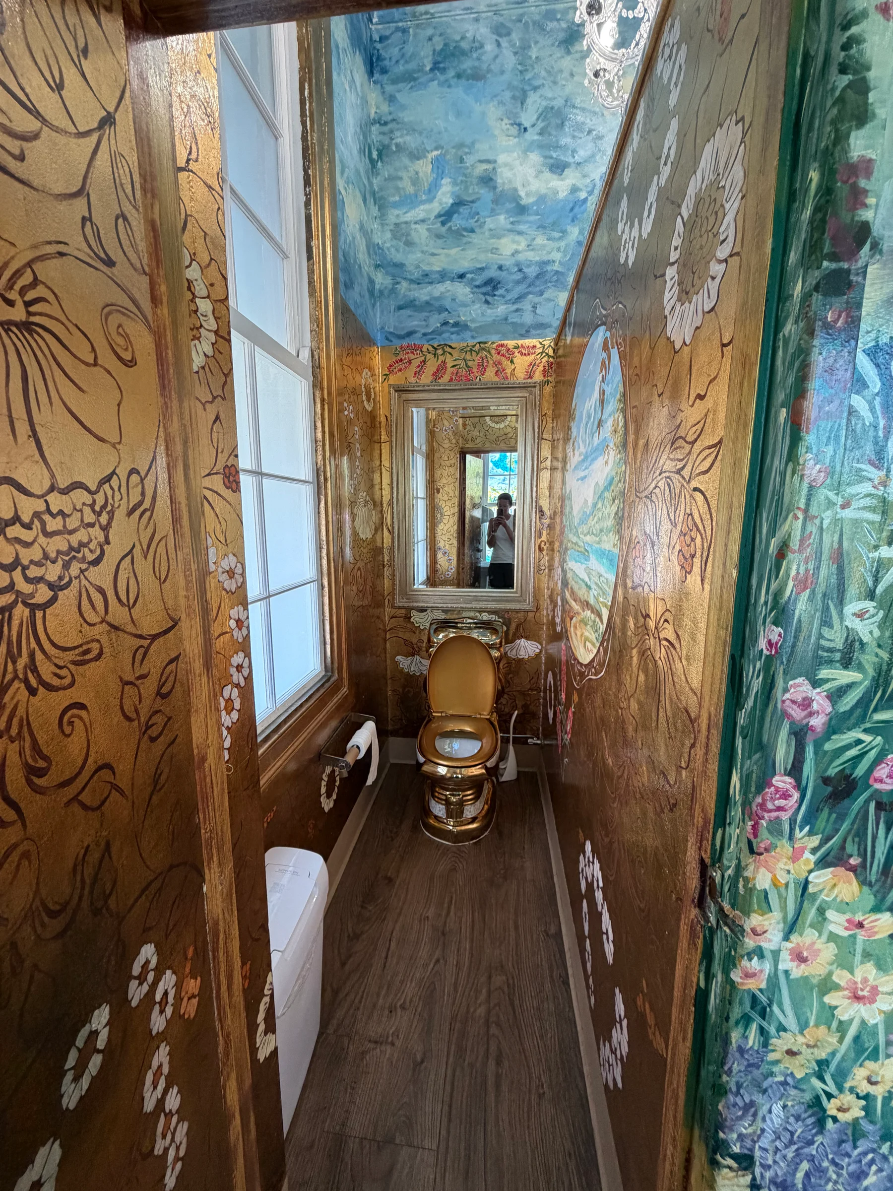 A long corridor with an elaborately painted arched ceiling and polished timber floor, detailed floral motifs running the full length.