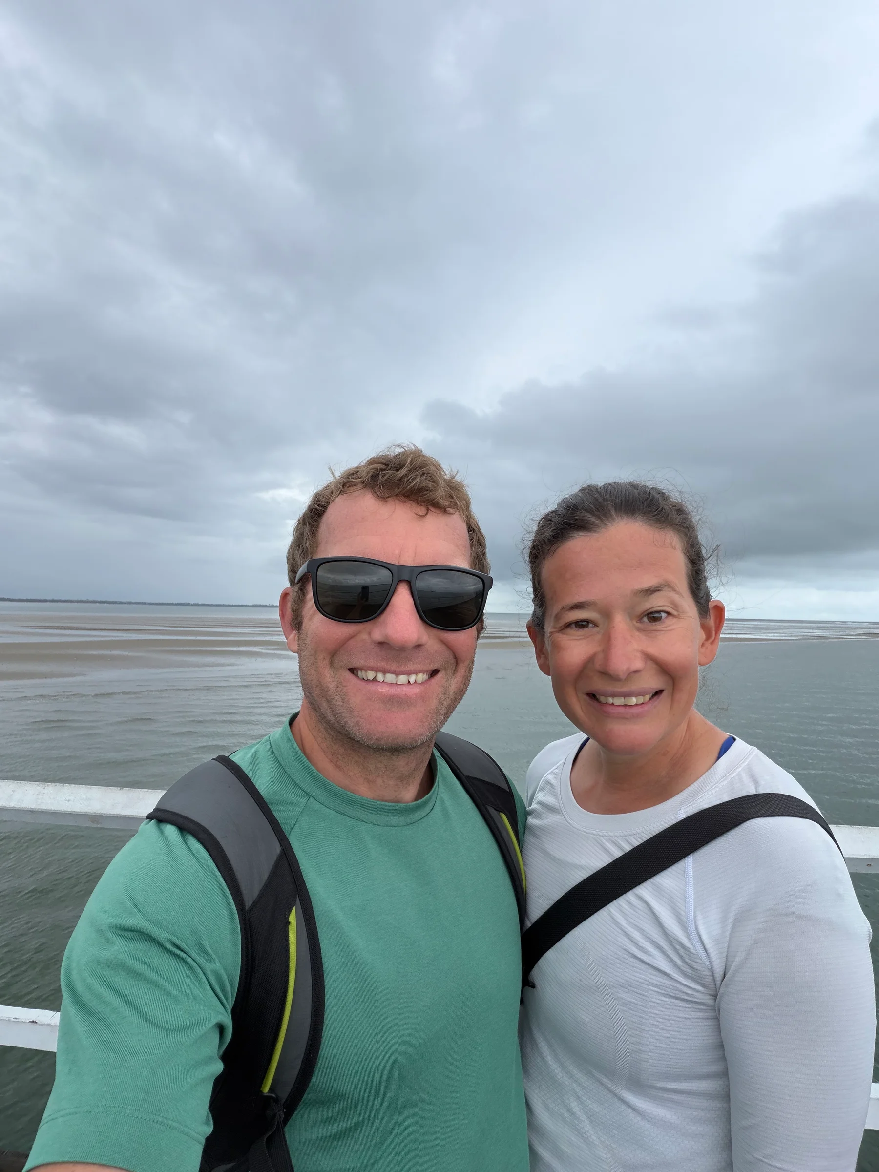 Matthias and Steph smiling together at the Hervey Bay pier, the water visible behind them.