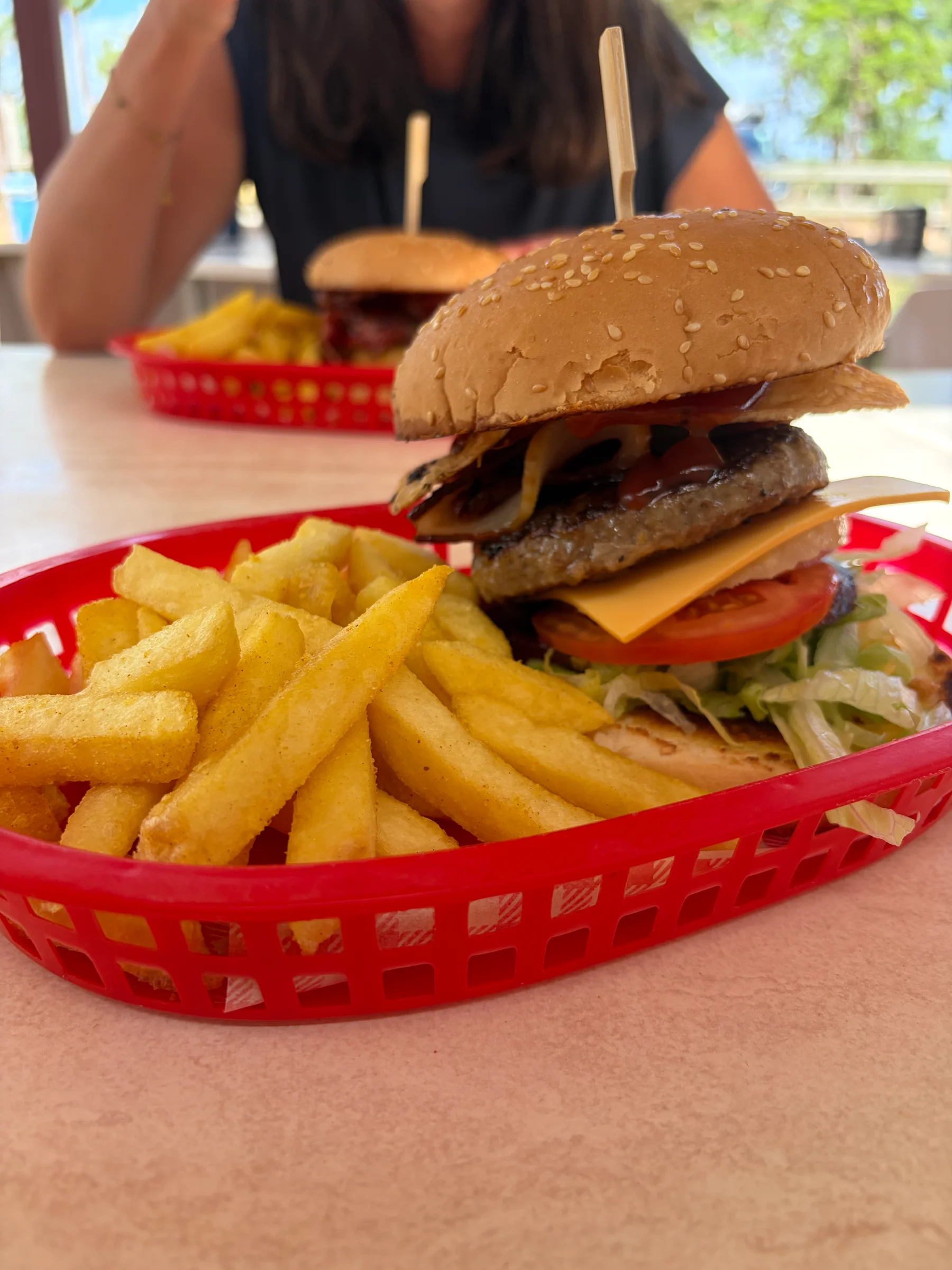 A roadhouse burger with a large serving of chips in a red plastic basket