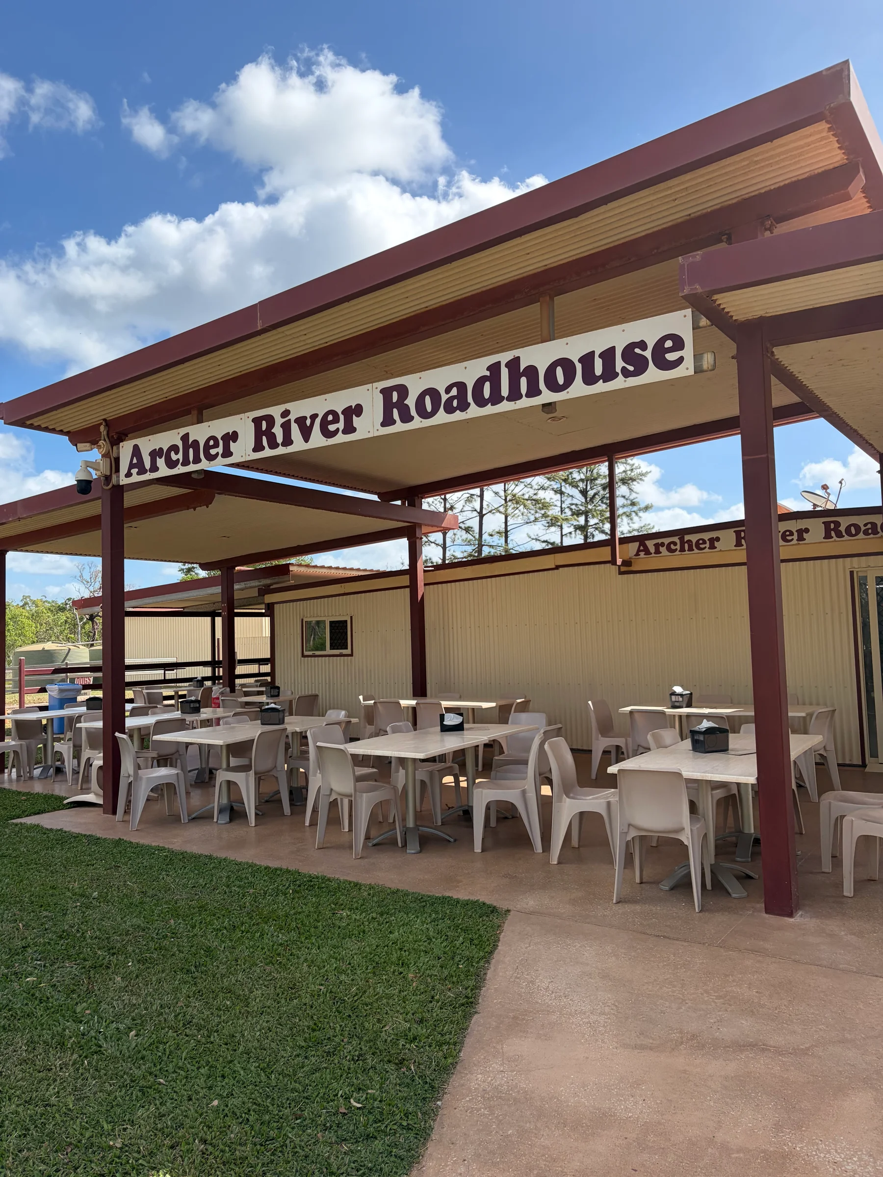 Covered outdoor seating area at Archer River Roadhouse with the roadhouse sign above
