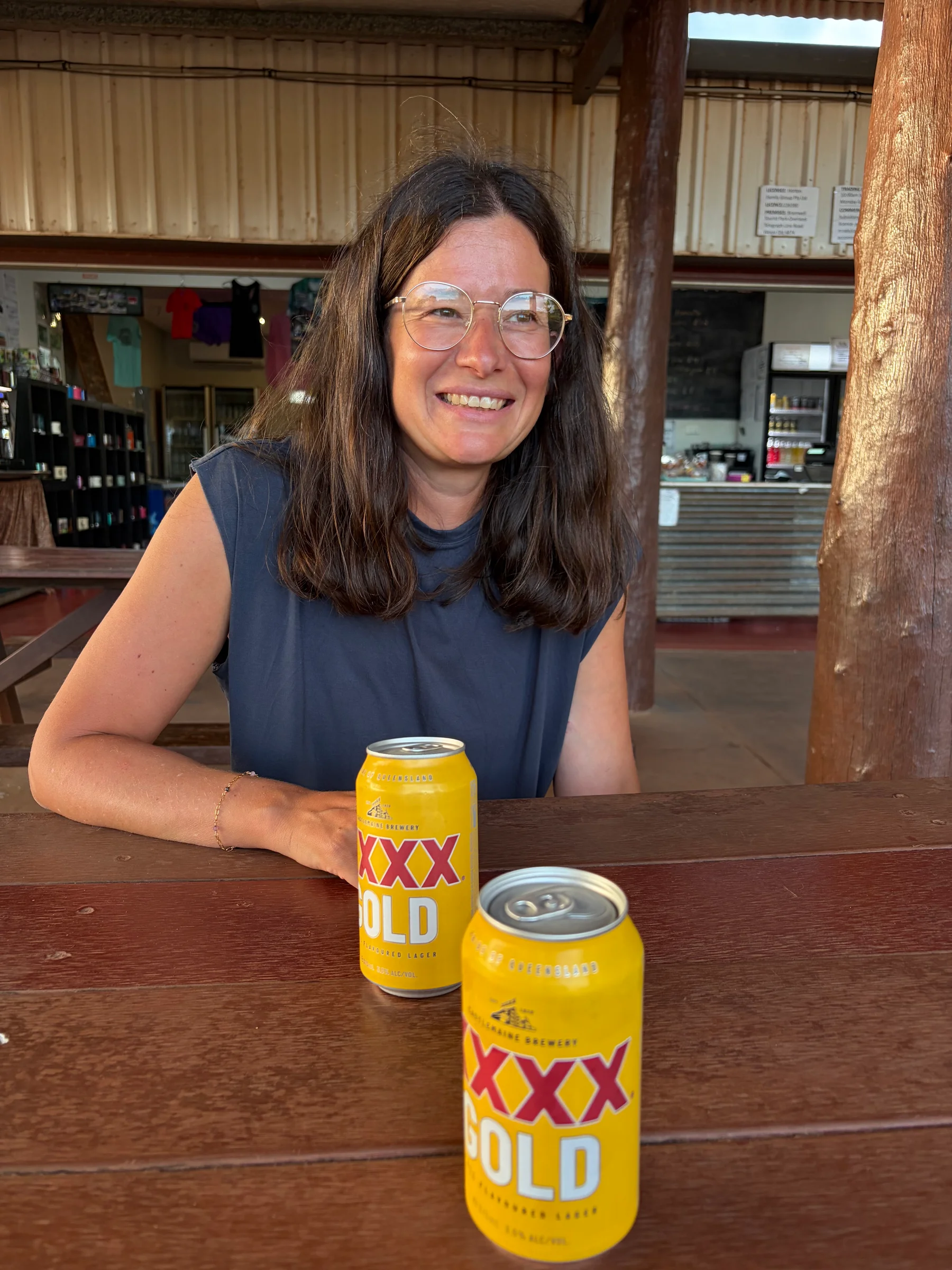 Steph smiling at the bar at Bramwell Junction Roadhouse with a XXXX Gold can in front of her