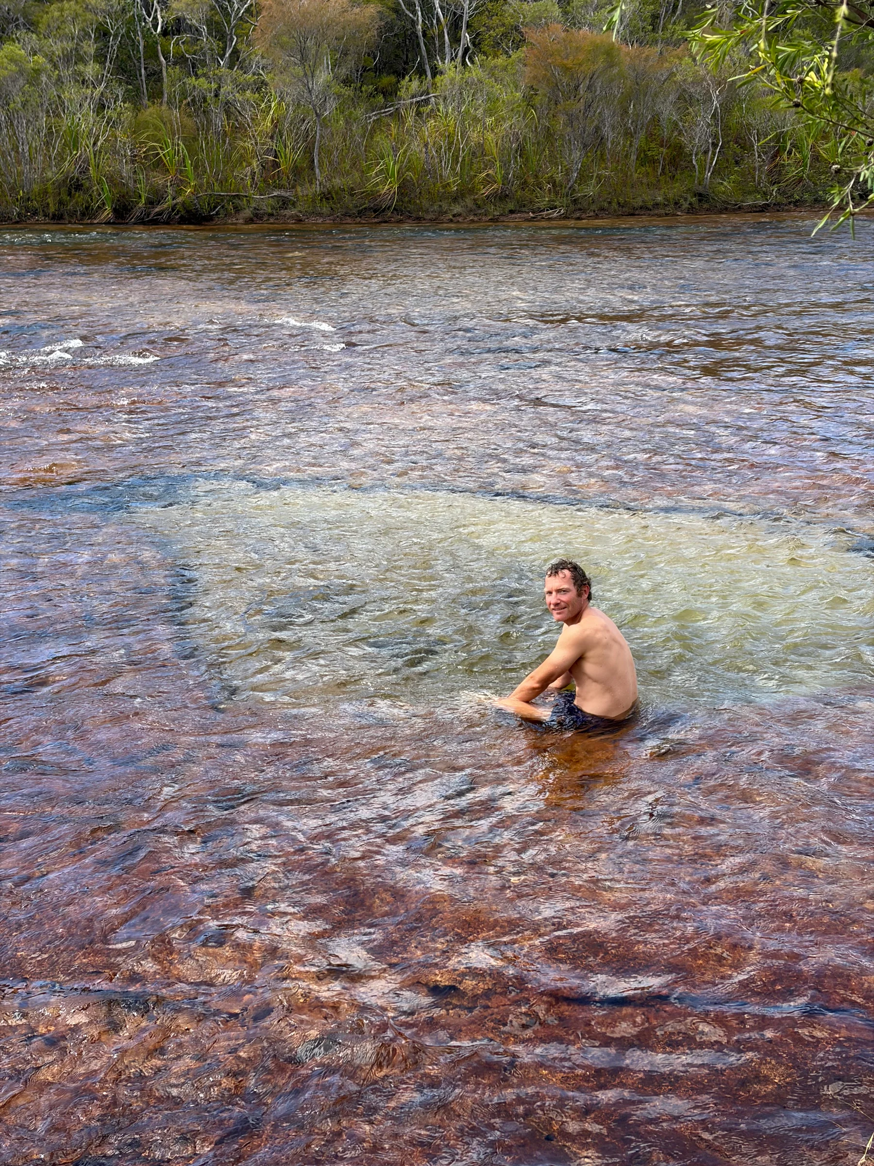 Matt wading in the clear water at Fruit Bat Falls, smiling at the camera